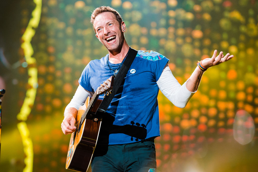 coldplay makes hundreds of millions of dollars chris martin of coldplay singing on stage with his guitar
